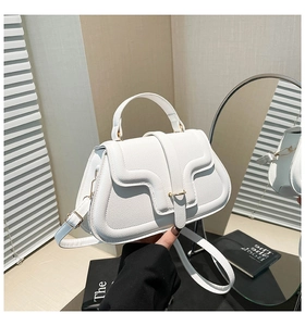 Detail view of white lychee leather handbag with wavy flap and gold metal buckle