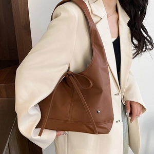 Brown retro tote bag with heart charm and drawstring detail worn over the shoulder