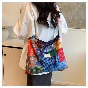 Detail of bohemian patchwork denim tote bag with drawstring closure and colorful patterns
