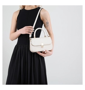 Detail of cream white crossbody bag with gold rotating lock and smooth leather texture