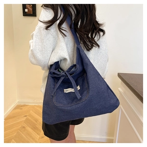 Détail du grand cabas en denim bleu foncé avec nœud latéral et étiquette tissée blanche