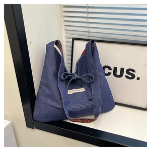 Detail of blue denim tote bag featuring ethnic patterned lining and bow tie decoration