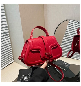 Detail of red lychee texture leather handbag with flap closure and metallic buckle
