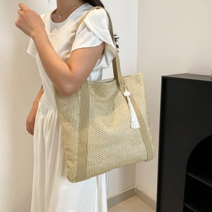 Minimalist large capacity woven tote bag for women featuring a stylish white tassel charm