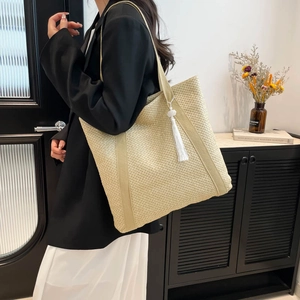 Minimalist beige woven tote bag with white tassel detail and slim shoulder straps