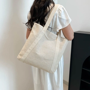 Minimalist large woven tote bag in creamy white for women shown on a model indoors
