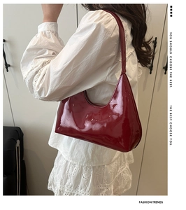 Detail view of deep red patent leather hobo bag worn with white embroidered top
