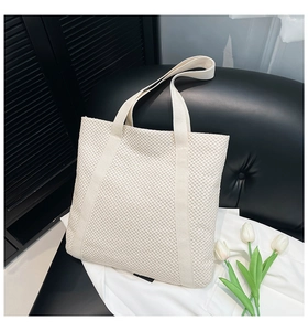 Détail de la texture en maille tissée et des larges bandoulières sur un sac blanc
