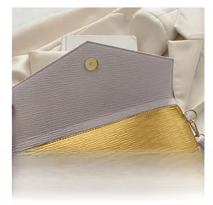 Detail of metal magnetic buckle on cream envelope clutch with wavy texture