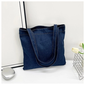 Detail view of a large denim tote bag with contrast orange stitching and double straps