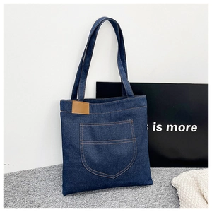 Détail du sac cabas en denim avec grande poche et étiquette en cuir marron