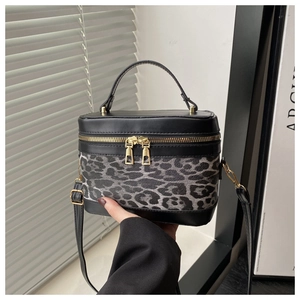 Détail du sac seau léopard avec fermetures éclair dorées et poignée en cuir noir