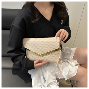 Dettaglio pochette beige con trama ondulata 3D e decorazione in metallo dorato a forma di V