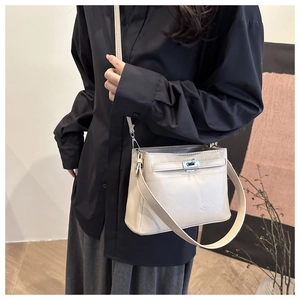 Detail of a creamy white glossy leather tote bag with silver metal twist lock closure