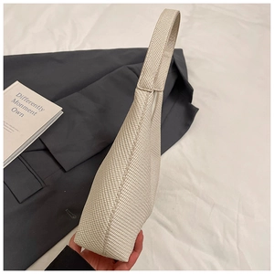 Detailed view of cream-white woven hobo bag with sleek minimalist shoulder strap design