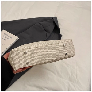 Detail of woven texture handbag base featuring four silver protective metal studs