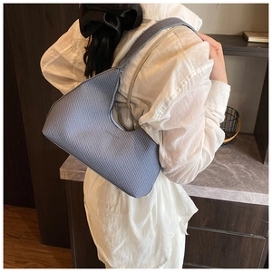 Detail of light blue underarm bag with geometric texture and fashion logo print