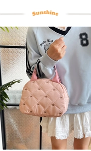 Sac à main matelassé rose avec broderie de nœuds et anse large porté par le modèle