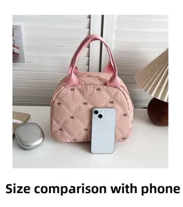 Détail du sac cabas rose matelassé avec nœud comparé à la taille d'un smartphone