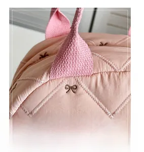 Détail du sac cabas matelassé rose montrant le nœud brodé et la qualité des coutures