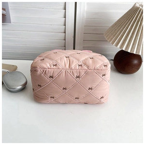 Détail du tissu matelassé rose avec broderies de nœuds sur un sac à main élégant