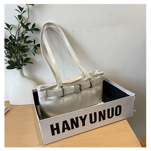 Detail view of cream leather tote bag with silver buckle in minimalist gift packaging