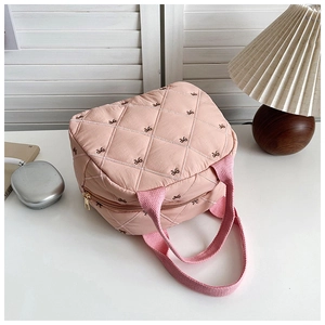 Détail de la trousse maquillage matelassée rose avec broderie nœud et poignée supérieure