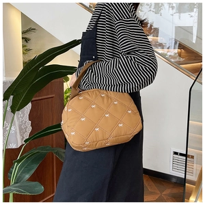 Détail d'un sac à main matelassé marron avec nœuds blancs et bandoulière large