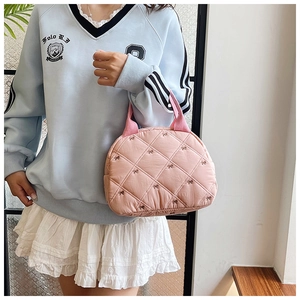 Vue détaillée du sac matelassé rose avec broderie nœud et poignées en ruban