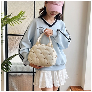 Détail du sac à main matelassé blanc cassé avec broderie nœud délicate et poignées robustes