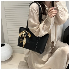 Detail einer schwarzen Leder-Shopper-Tasche mit weißen Nähten und gelbem Blumenschal-Akzent