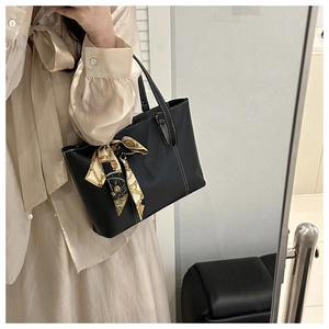 Detailansicht einer schwarzen Shopper-Tasche mit Kontrastnaht und gemustertem Seidentuch