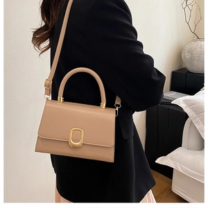 Detail of minimalist beige leather crossbody bag with elegant golden oval metal buckle