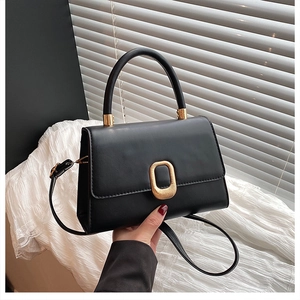 Detail of minimalist black PU leather handbag with golden oval buckle and adjustable strap