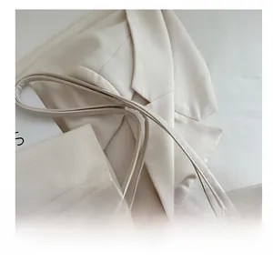 Detail of light beige tote bag with M-letter jacquard pattern and premium leather handles