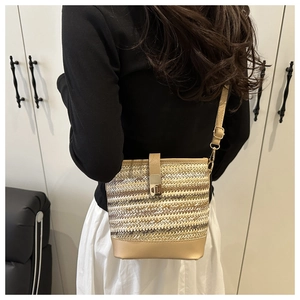 Détail du sac seau en paille tressée avec base en cuir beige et bandoulière réglable