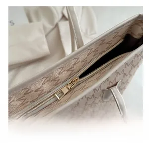 Close-up of the smooth golden zipper and beige jacquard fabric with M-letter pattern