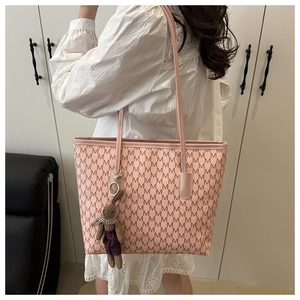 Pink tote bag with letter pattern and rabbit plush charm shown on a female model