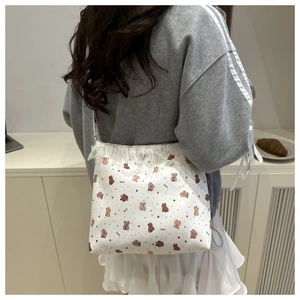 Detailed view of the lace trim and cute cartoon bear print on the white canvas shoulder bag