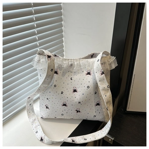 Detail of white canvas tote featuring colorful bear prints and elegant lace ruffle edges