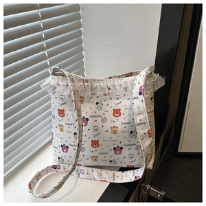 Detail of white canvas tote bag featuring colorful cartoon bear prints and lace trim