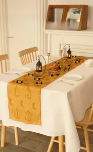 Detail showing moon and lantern embroidery with tufted textures on yellow table runner