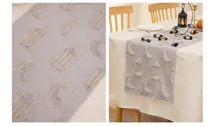 Detail of moon and lantern embroidery on a textured grey-blue table runner