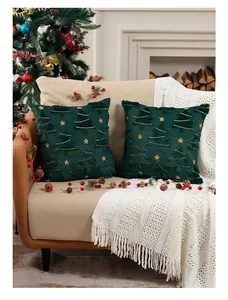 Detalle de cojines navideños de felpa verde bosque con estrellas y árboles bordados oro