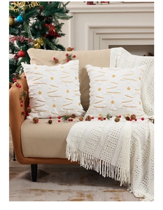 Detalle de fundas de cojín de felpa blanca con árboles de Navidad bordados en oro