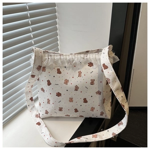Detail of white canvas shoulder bag with bear print and delicate lace trim edge