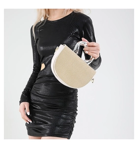 Dettaglio borsa a mezzaluna beige intrecciata con manico in metallo e finiture in pelle bianca