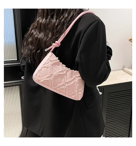Dettaglio della borsa a spalla in denim rosa trapuntato con un elegante blazer nero