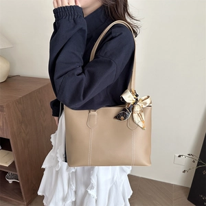 Minimalistische beige Leder-Tote-Bag mit Vintage-Schal am Griff und weißer Naht