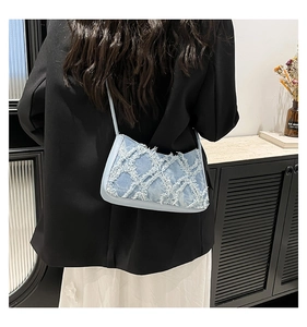 Detail of blue denim shoulder bag featuring frayed edges and textured diamond pattern